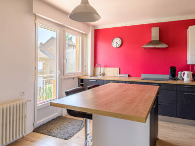 Cuisine moderne avec mur rouge et îlot central.