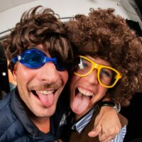Personnes joyeuses avec lunettes et perruques rigolent.