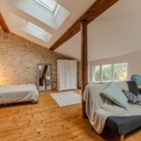 Chambre mansardée avec pierres apparentes et fenêtres de toit.