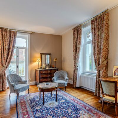 Salon élégant avec meubles anciens et tapis coloré.