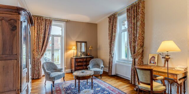 Salon élégant avec meubles anciens et tapis coloré.