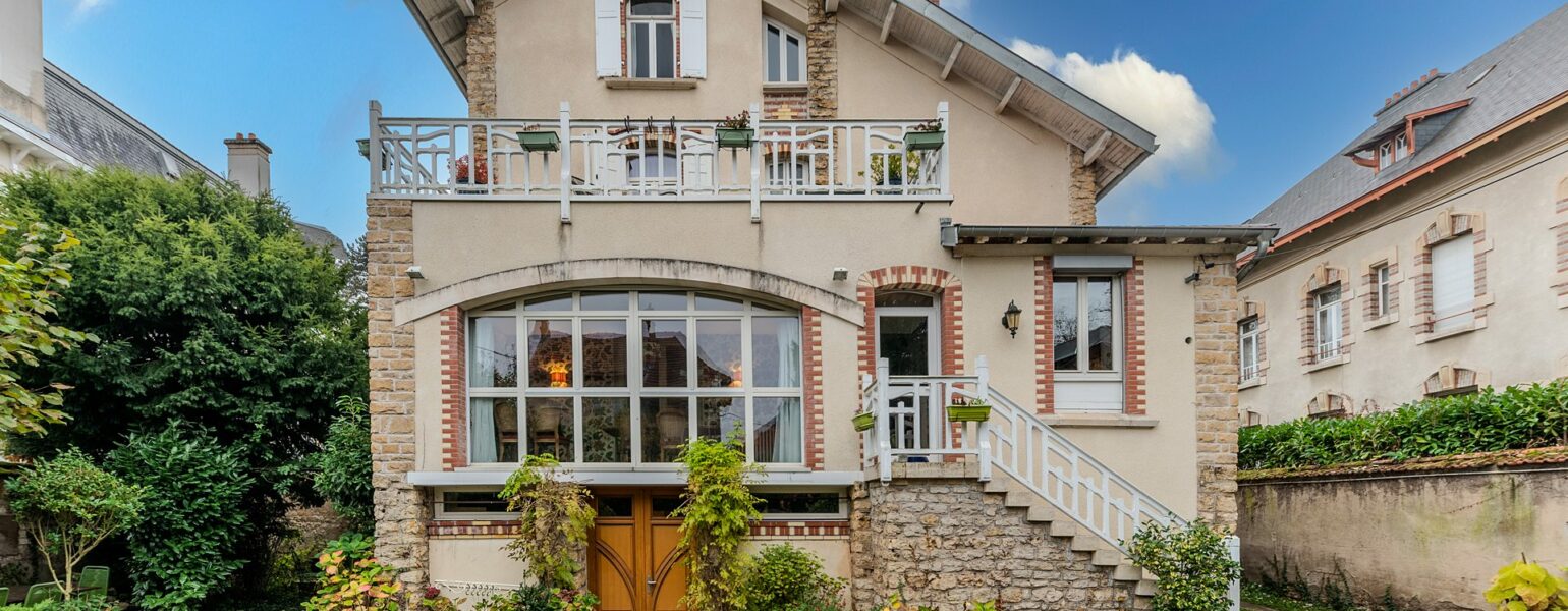 Maison en briques avec jardin, ciel bleu.