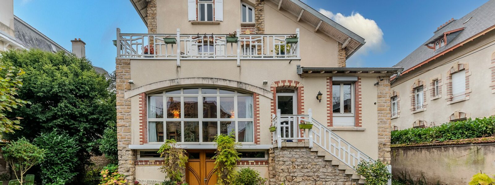 Maison en briques avec jardin, ciel bleu.