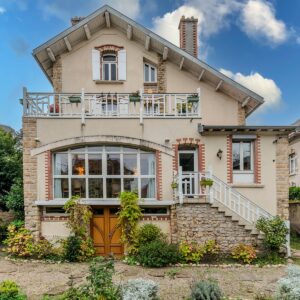 Maison en briques avec jardin, ciel bleu.