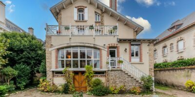 Maison en briques avec jardin, ciel bleu.