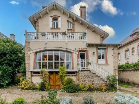 Maison en briques avec jardin, ciel bleu.