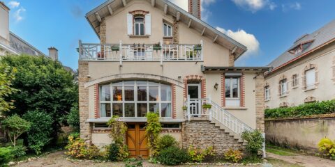 Maison en briques avec jardin, ciel bleu.