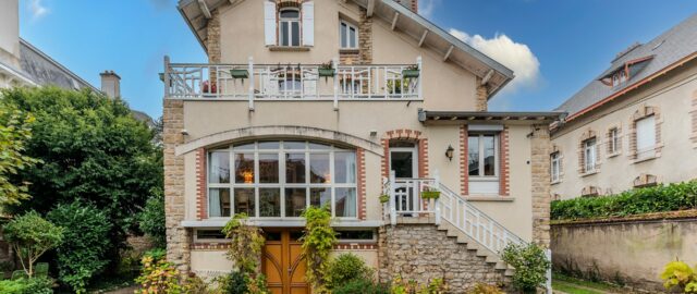 Maison en briques avec jardin, ciel bleu.