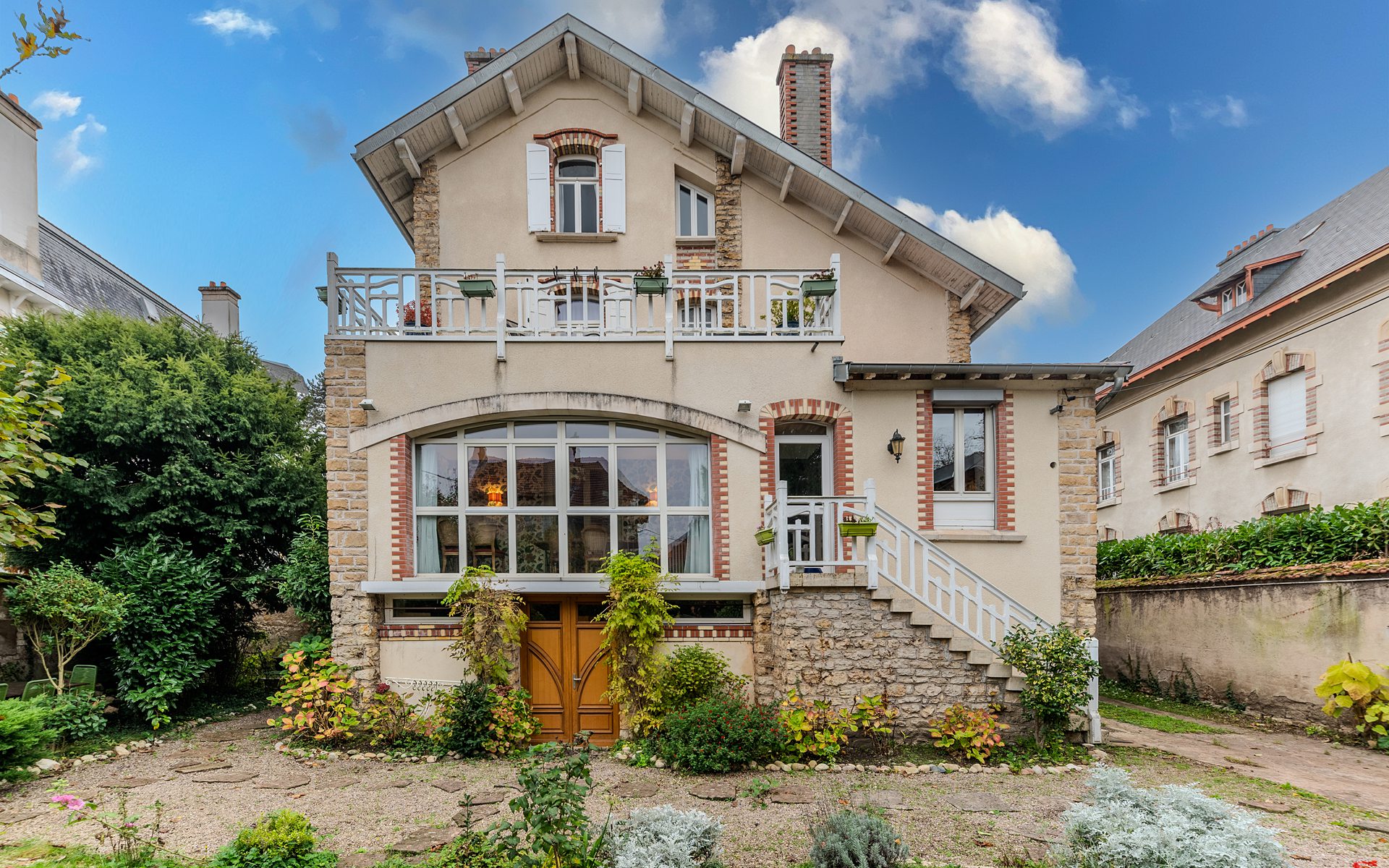 Maison en briques avec jardin, ciel bleu.