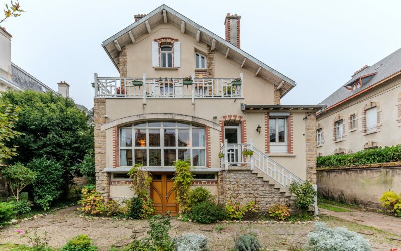 Maison en pierre avec jardin et balcon.