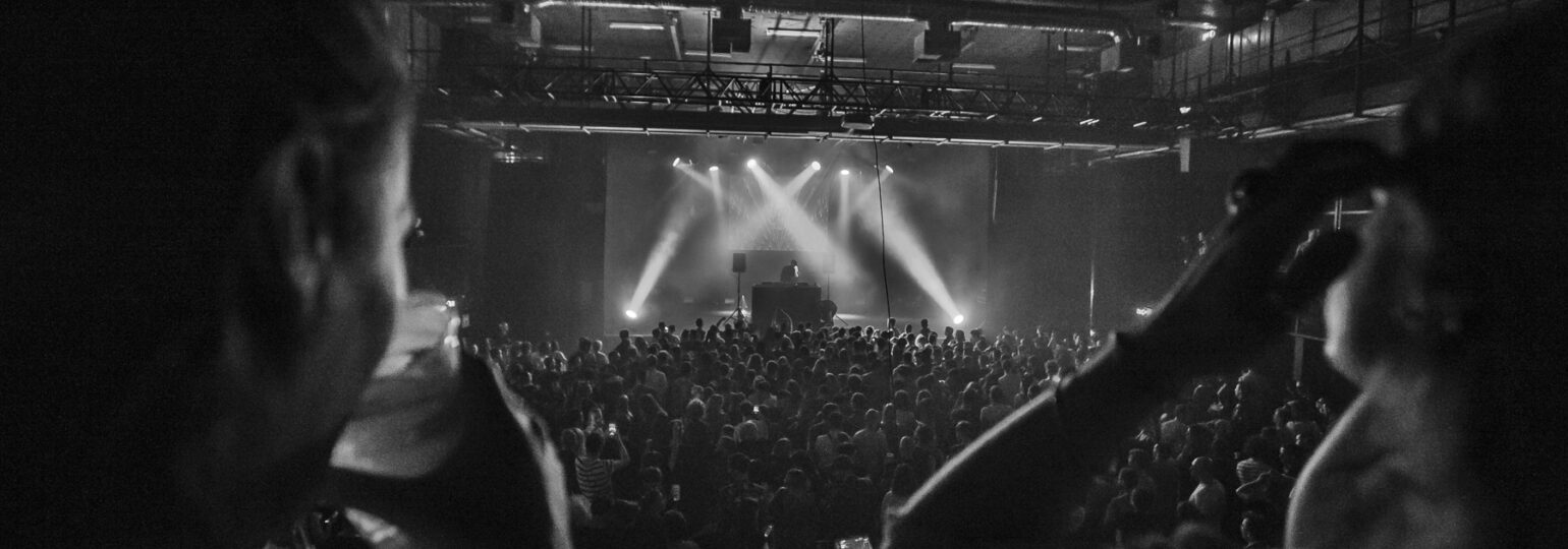 Concert en noir et blanc avec public enthousiaste.