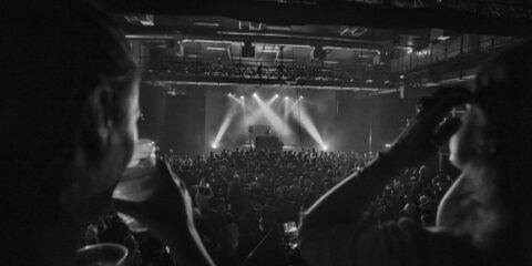 Concert en noir et blanc avec public enthousiaste.