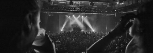 Concert en noir et blanc avec public enthousiaste.