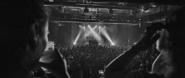 Concert en noir et blanc avec public enthousiaste.