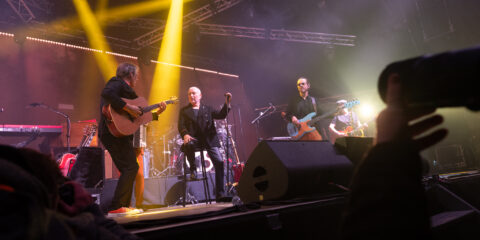 Concert avec groupe jouant sur scène éclairée.