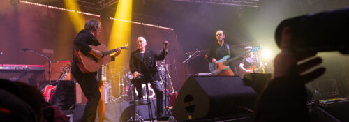 Concert avec groupe jouant sur scène éclairée.