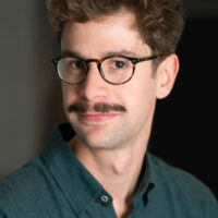 Portrait d'un homme avec lunettes et moustache.