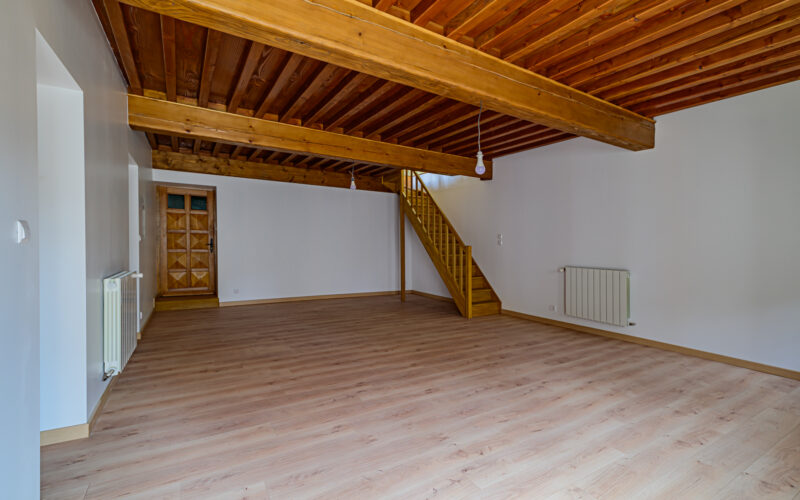 Salon vide avec plafond en bois et escalier