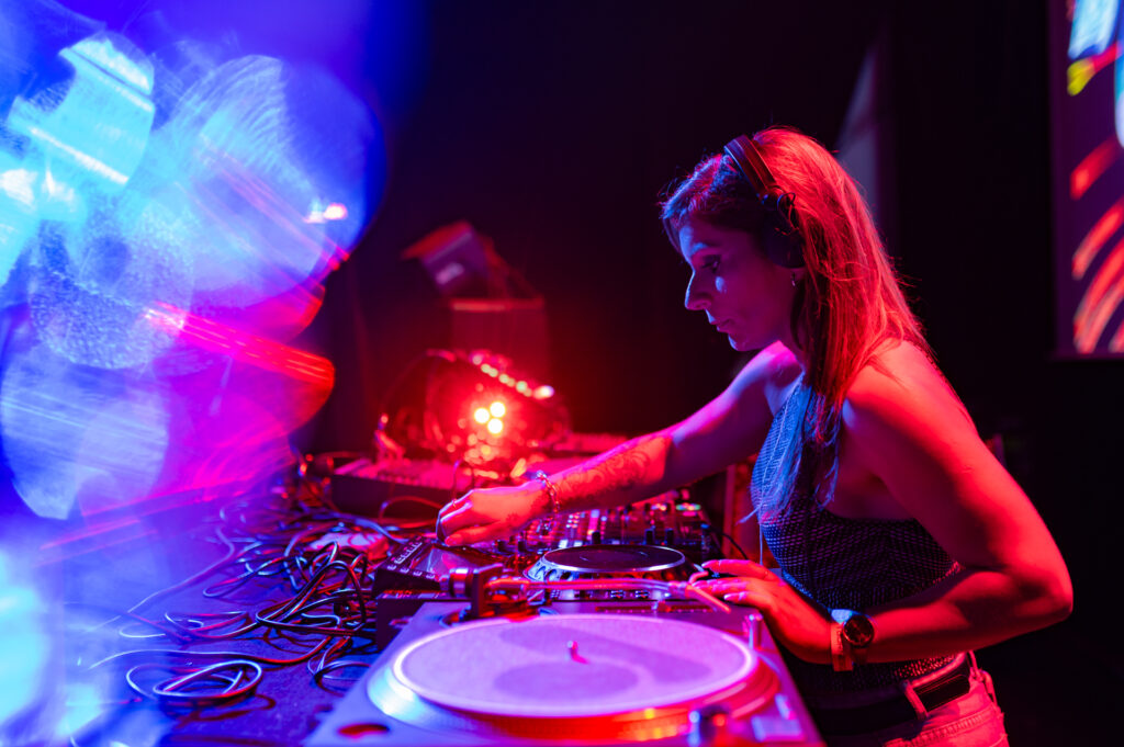 DJ mixant sur scène avec lumières colorées.