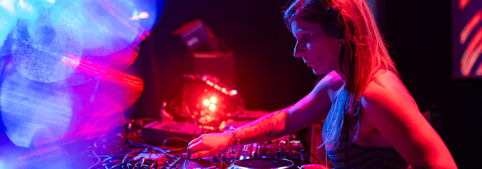 DJ mixant sur scène avec lumières colorées.