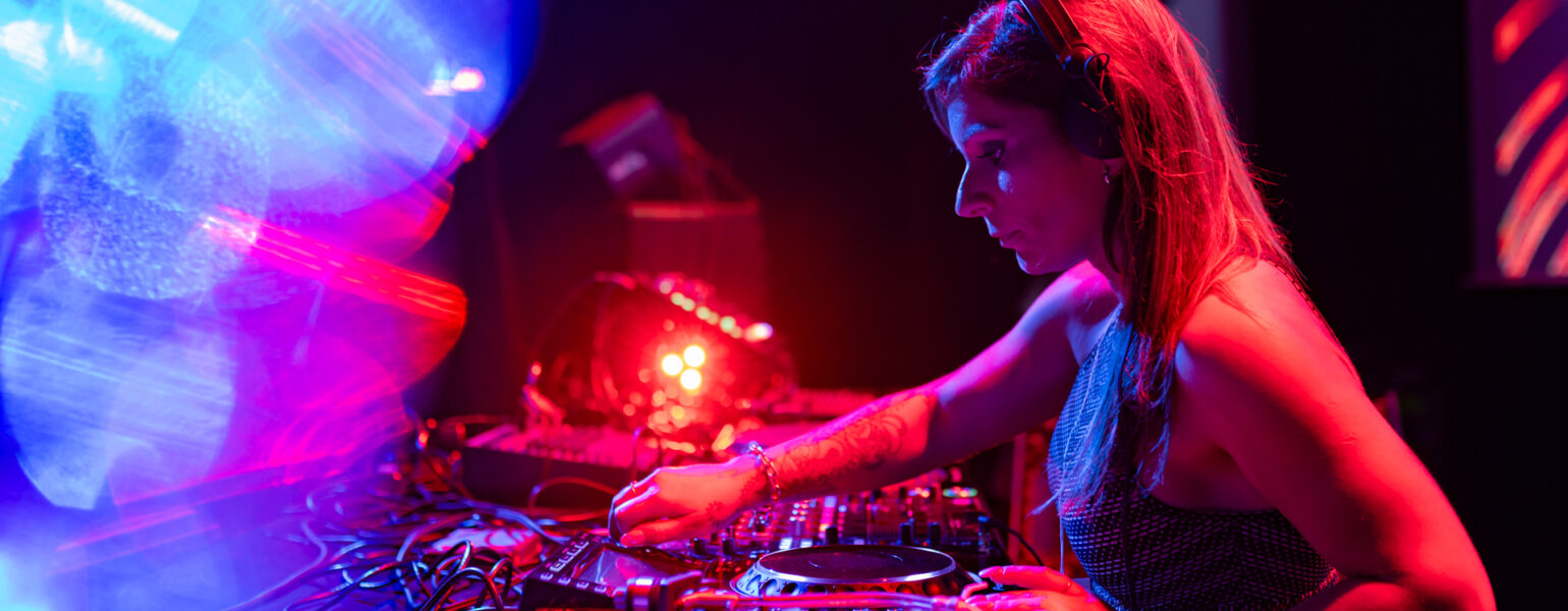 DJ mixant sur scène avec lumières colorées.