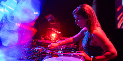 DJ mixant sur scène avec lumières colorées.