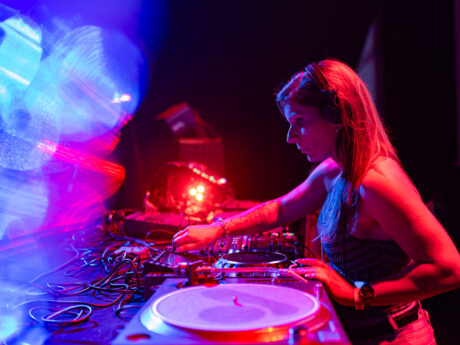 DJ mixant sur scène avec lumières colorées.