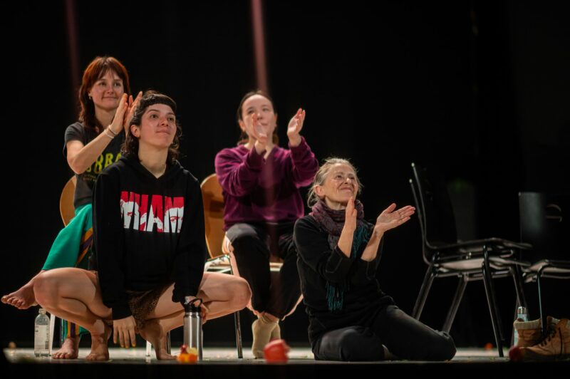 Quatre personnes assises applaudissant sur scène.