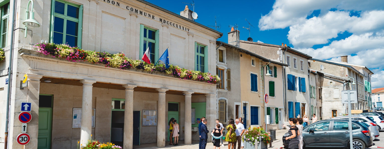 Mairie avec fleurs et personnes devant.