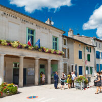 Mairie avec fleurs et personnes devant.