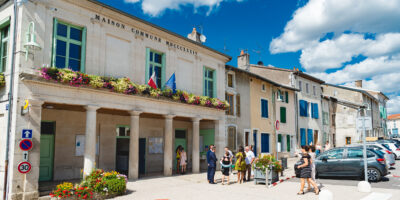 Mairie avec fleurs et personnes devant.