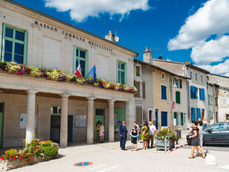 Mairie avec fleurs et personnes devant.