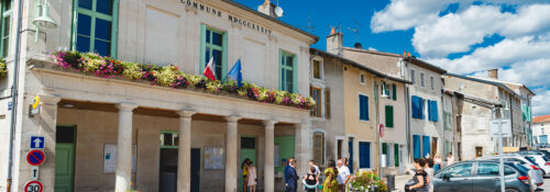 Mairie avec fleurs et personnes devant.