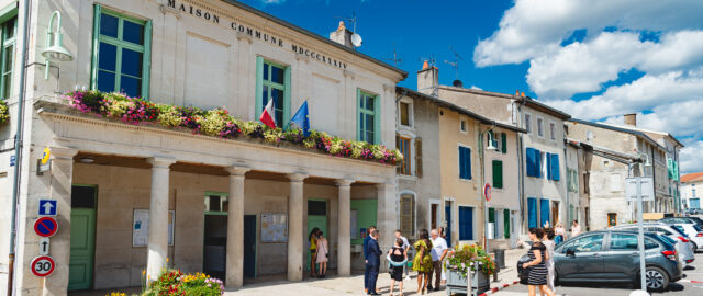 Mairie avec fleurs et personnes devant.