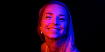 Femme souriante sous éclairage coloré.