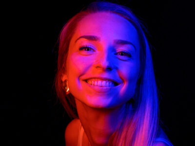 Femme souriante sous éclairage coloré.