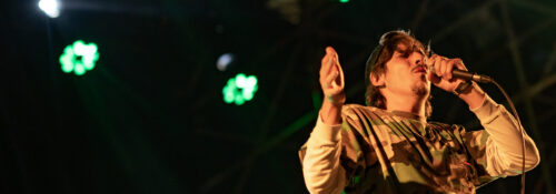 Portrait de Biga*Ranx en concert, mettant en avant son style unique mêlant dub et reggae, avec une ambiance lumineuse immersive.