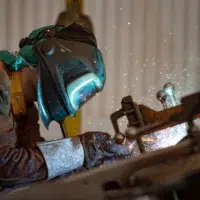 Ouvrier métallurgiste qualifié effectuant une opération de soudure ou de découpe sur une structure massive.