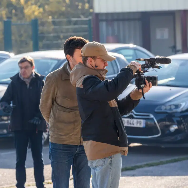 Un caméraman filmant une scène en extérieur avec sa caméra.