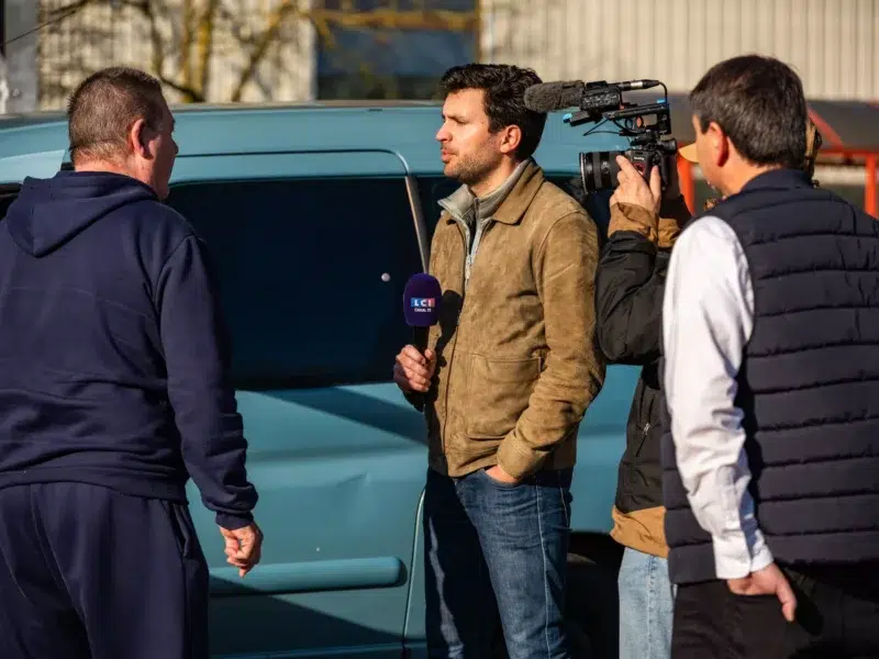 Un journaliste de LCI interviewe un homme en extérieur.