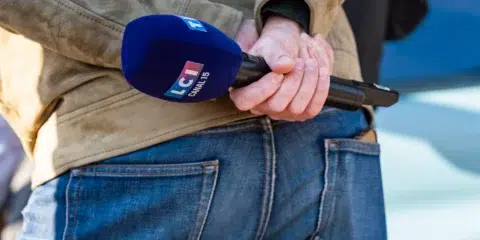 Journaliste de dos tenant un micro de la chaîne LCI.