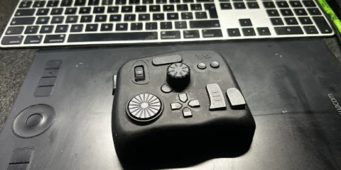 Contrôleur TourBox noir posé sur une tablette graphique Wacom.