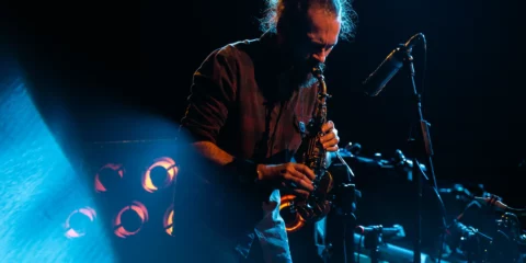 Saxophoniste jouant sur scène sous des éclairages bleus et oranges.