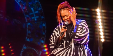Chanteuse en vêtement rayé chantant avec passion sur scène.