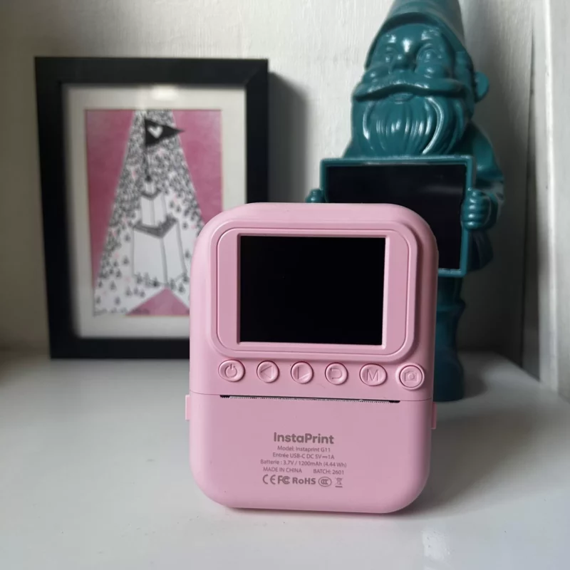 Imprimante photo de poche InstaPrint rose sur une étagère.