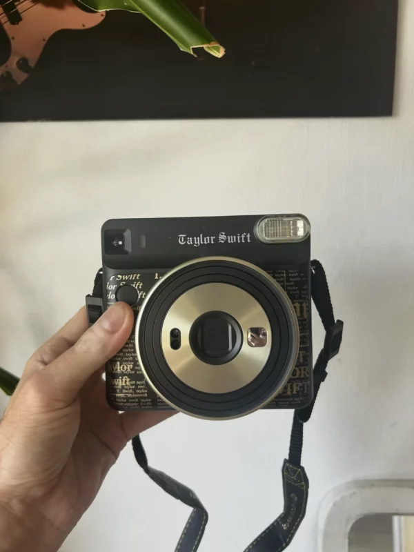 Appareil photo instantané Fujifilm Instax Taylor Swift tenu en main.