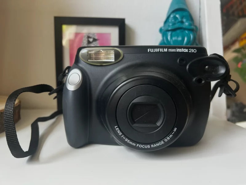 Appareil photo instantané Fujifilm Instax 210 noir sur une étagère.