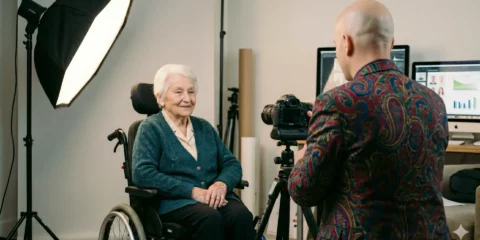 Photographe prenant le portrait d'une femme âgée en fauteuil roulant.