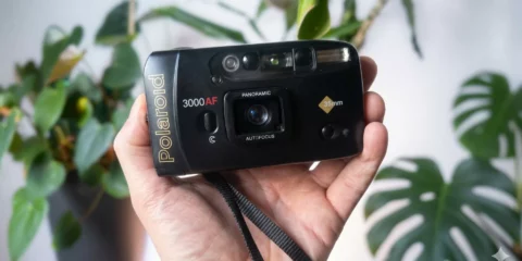Main tenant un appareil photo Polaroid 3000AF noir vintage.