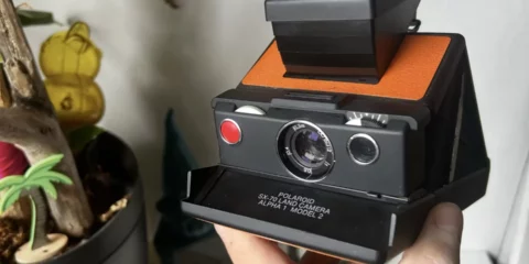 Appareil photo Polaroid SX-70 tenu par une main.